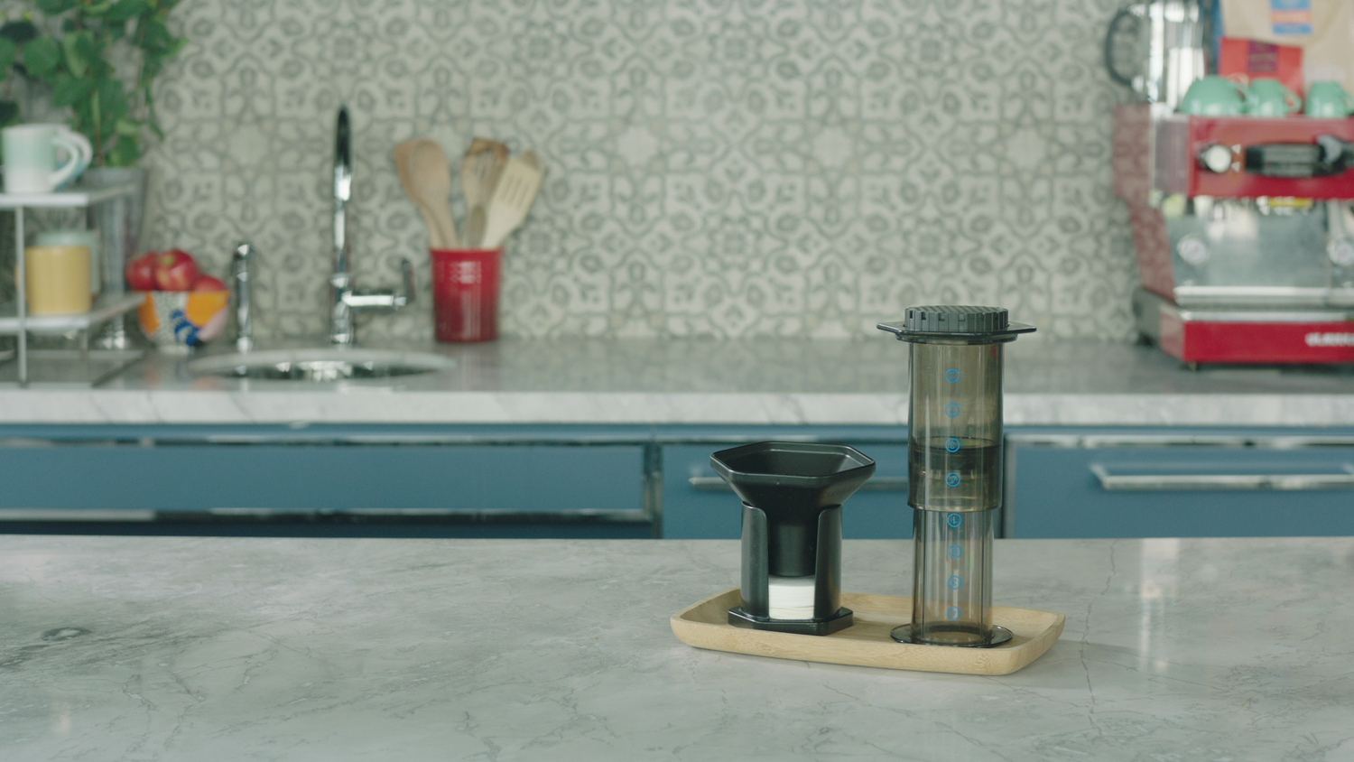 Front view of AeroPress and filter cap on a wooden tray showing chamber measurements on a marble counter
