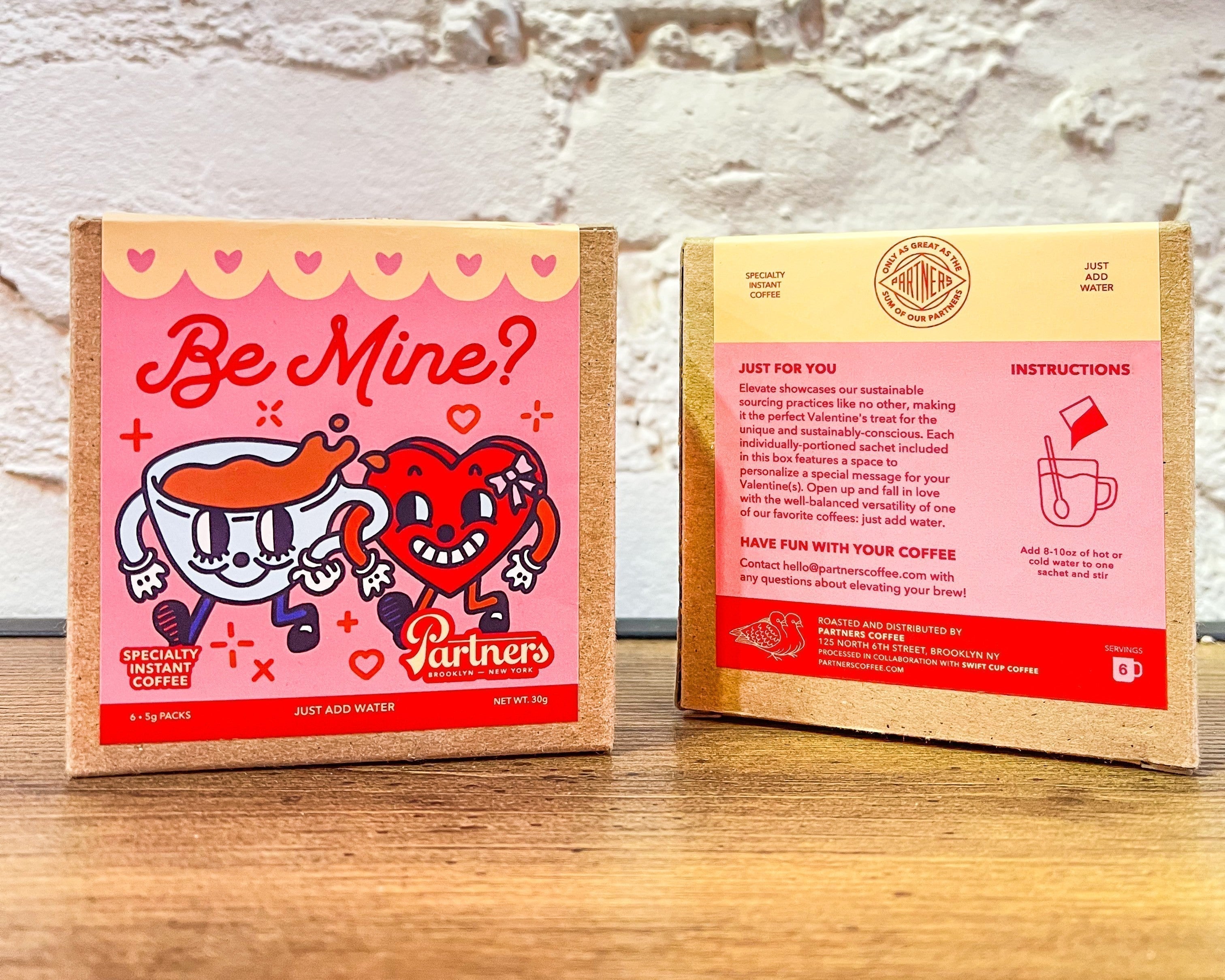 Front-and-back view of Partners Coffee Be Mine? instant coffee boxes with pink Valentine’s packaging and cartoon cup and heart
