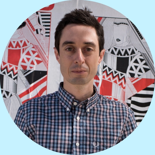 Ben, Partners Coffee director of operations, facing camera in front of a colorful geometric mural