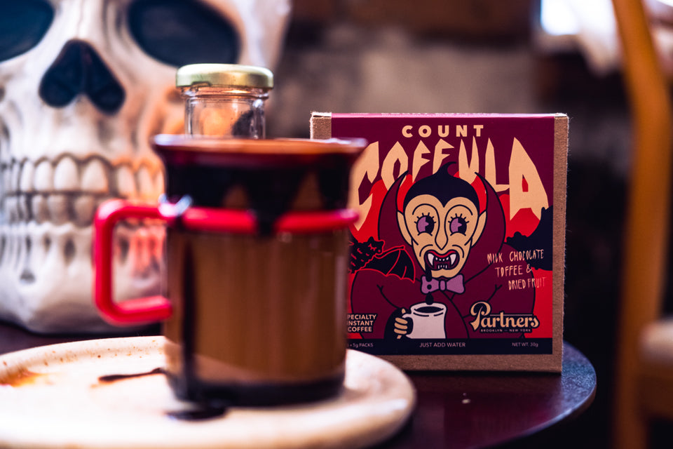 Boo Brew specialty instant coffee package beside a mug and skull decoration in a Halloween-themed setting