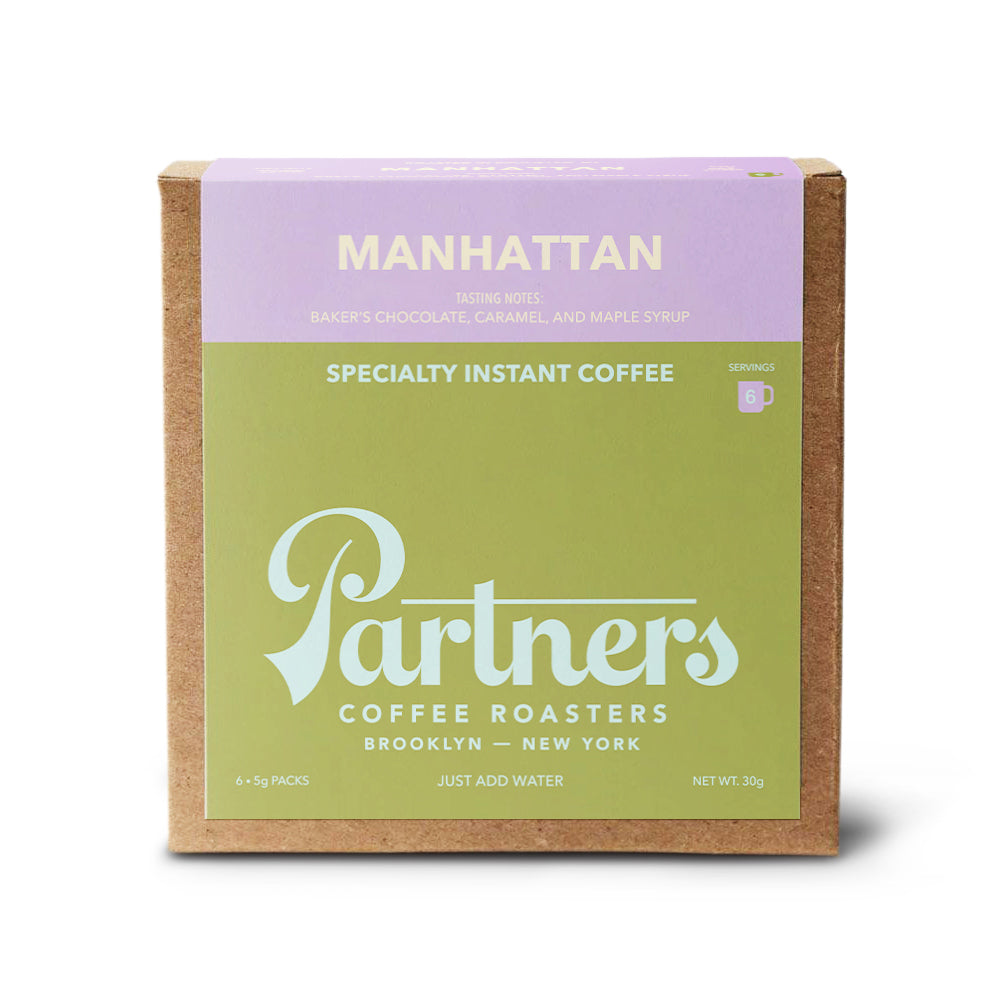 Front view of Manhattan specialty instant coffee box showcasing Partners logo and green and lavender front panel on white background