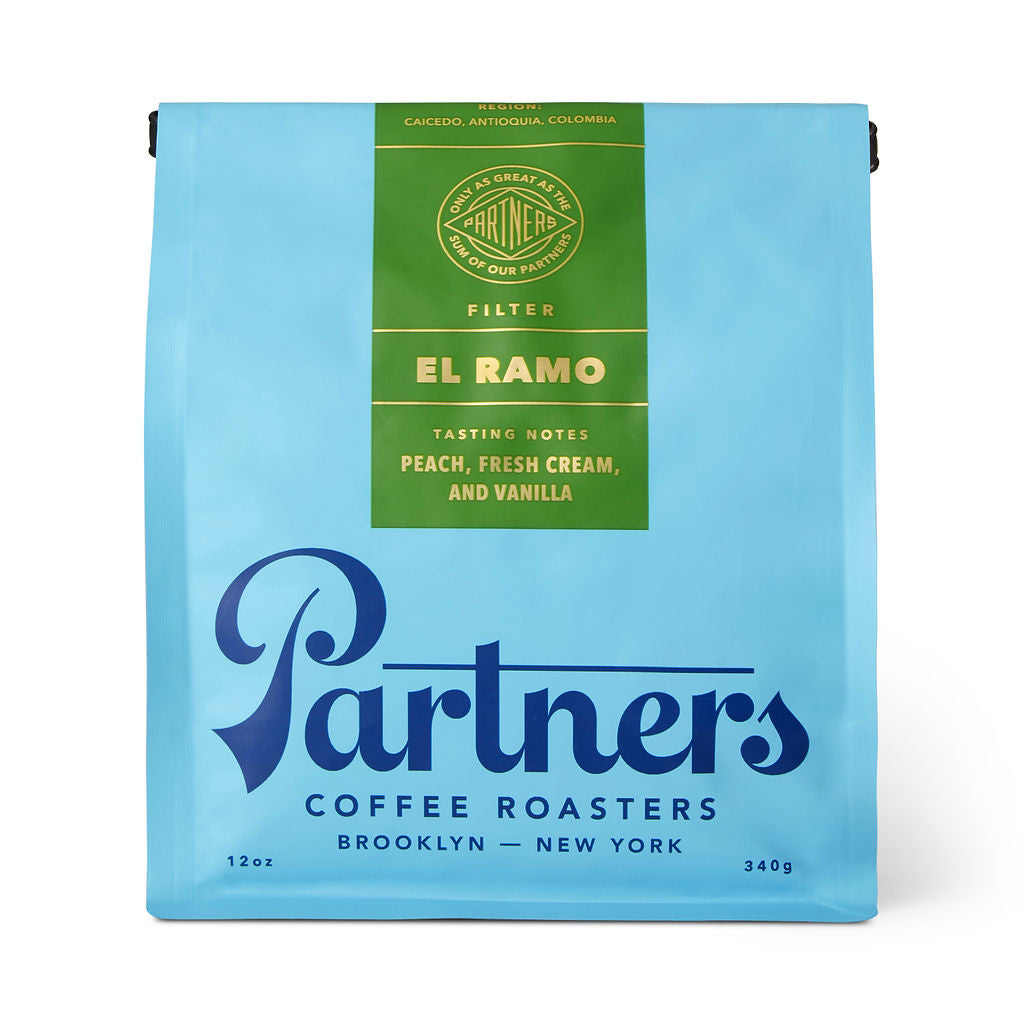 Front view of Colombia El Ramo coffee bag with light blue packaging, green label, and Partners logo on white background