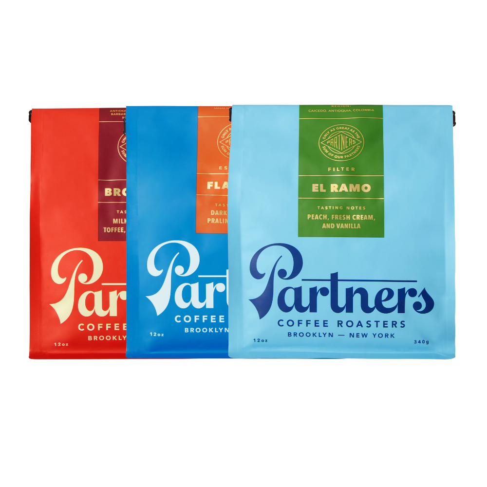 Front view of 3 x 12 oz. Partners coffee bags: Brooklyn red, Flatiron blue, El Ramo green on white background