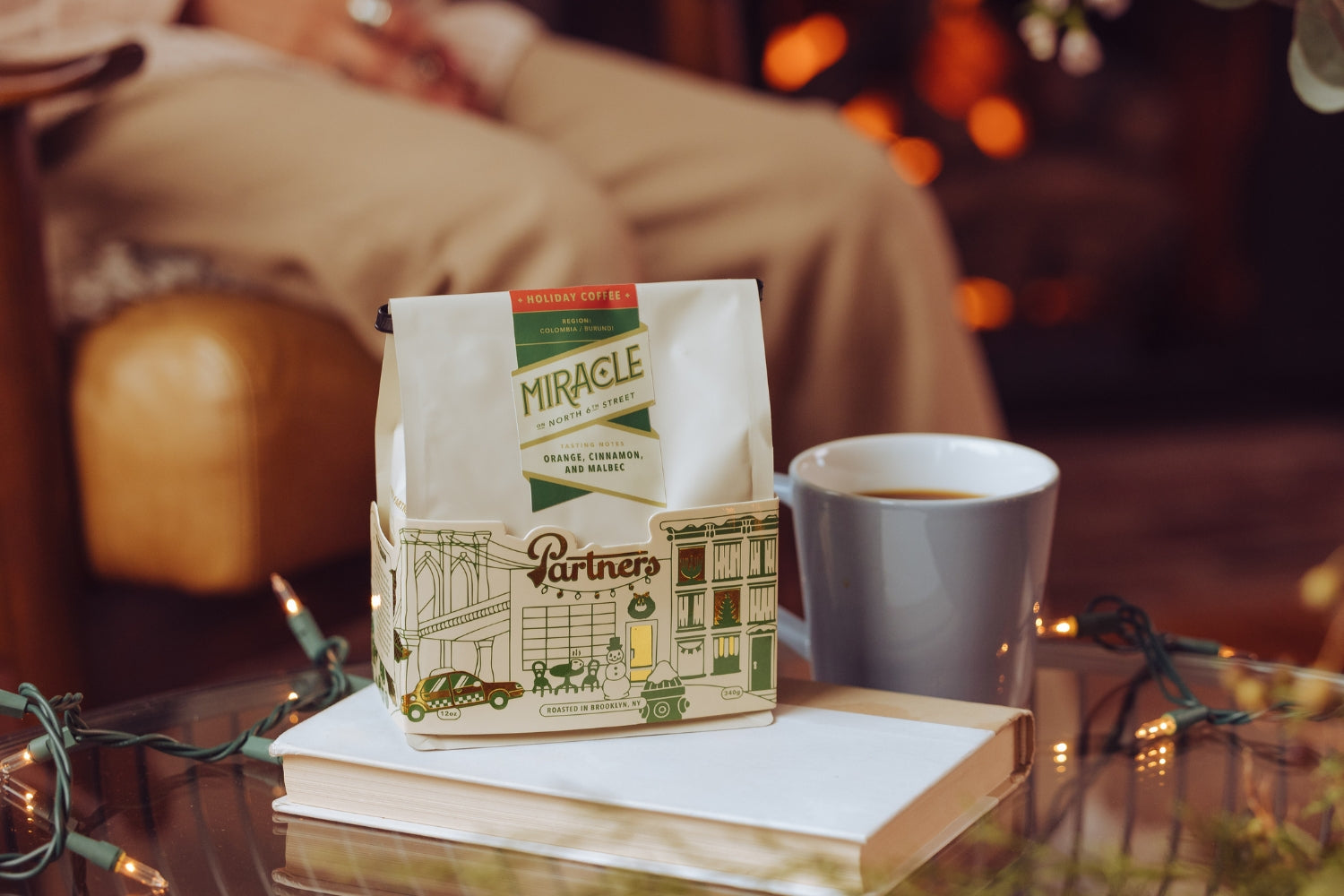 Front view of Miracle On North 6th Street (2023) holiday coffee bag showcasing Partners Coffee illustrated sleeve with mug and cozy holiday background