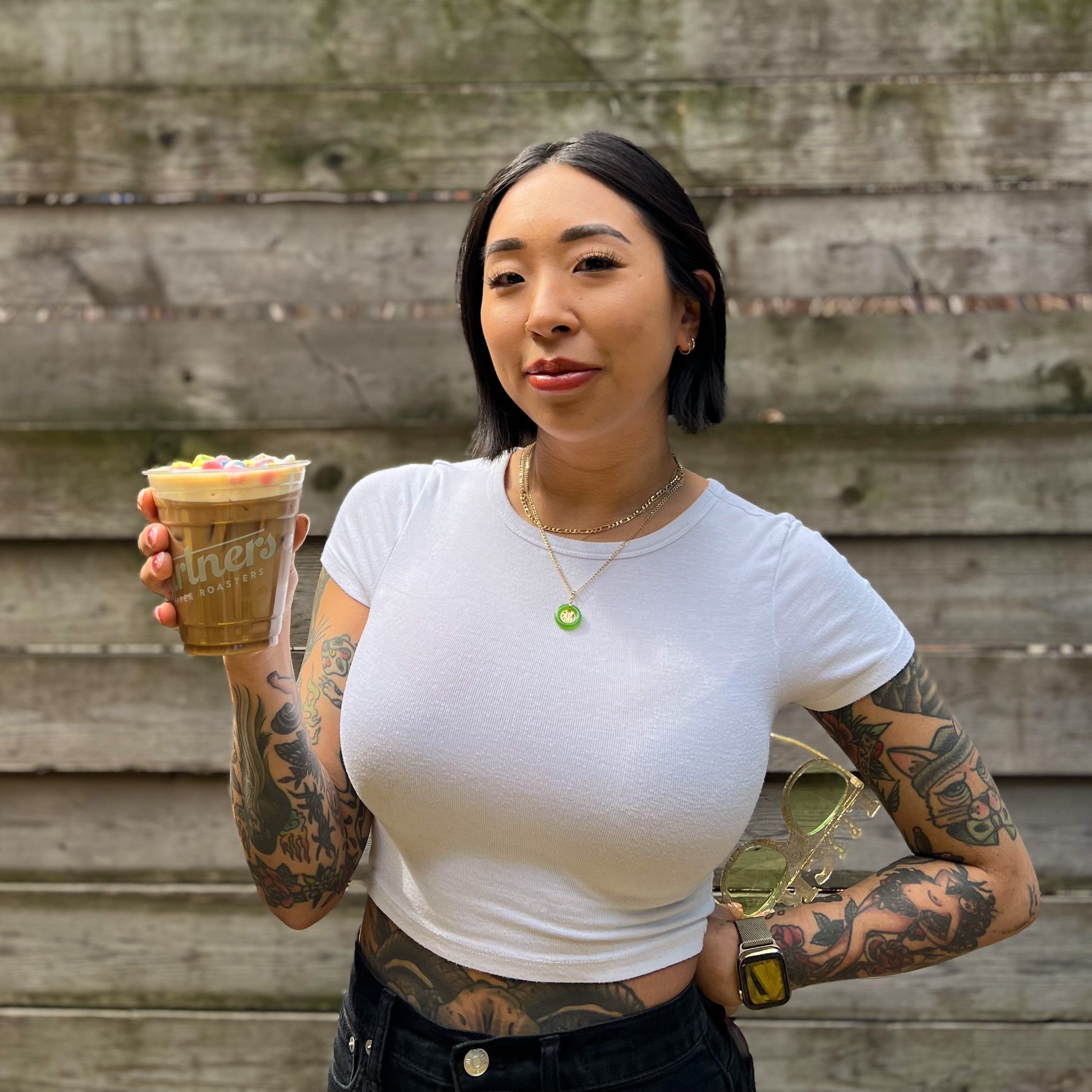 Barista holding a Partners Coffee Nutty Irishman cold brew topped with pastel candies in an outdoor courtyard