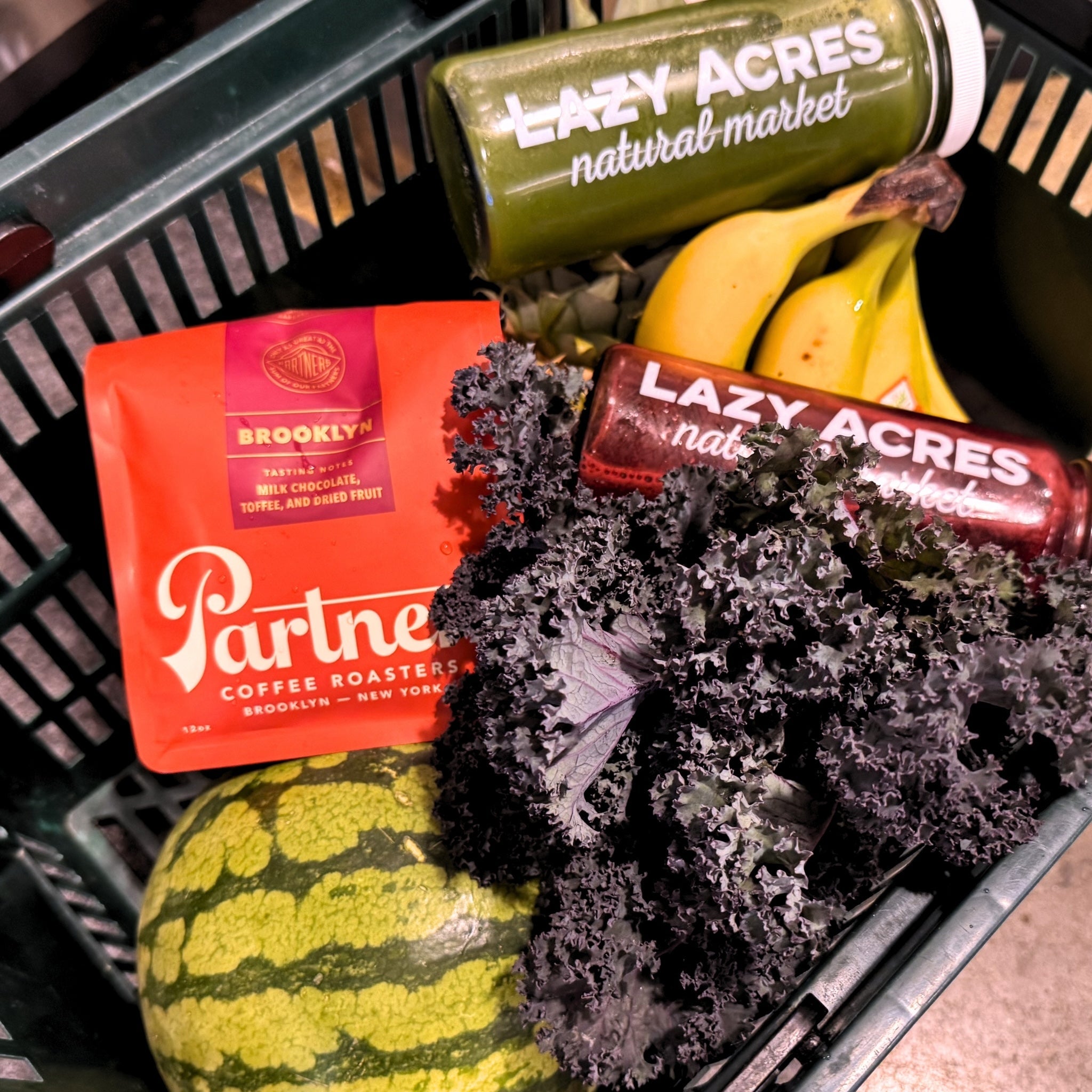Partners Coffee's Brooklyn blend in a basket alongside market favorites including fresh juices and produce