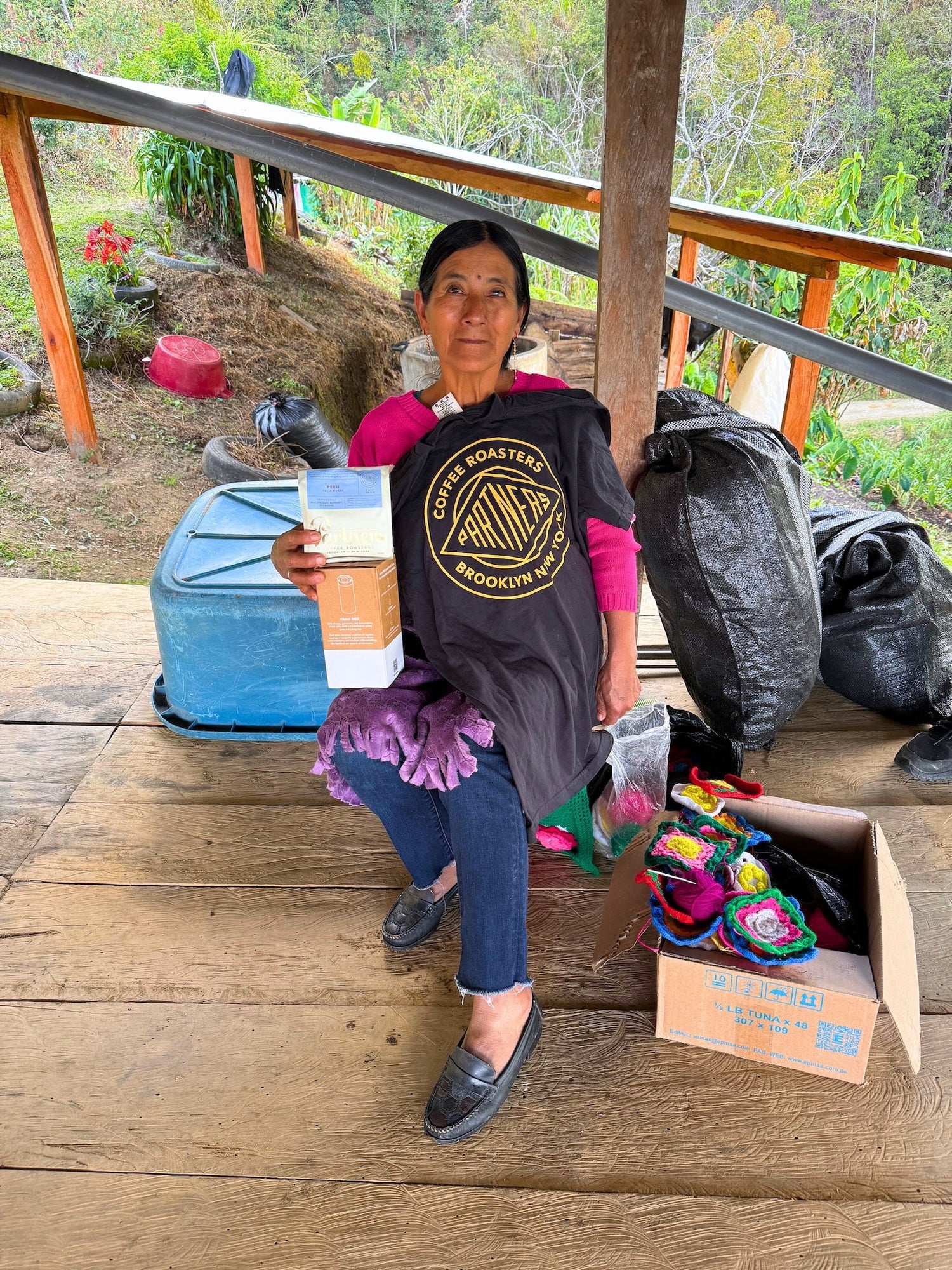 Producer Lucía Muñoz opening a Partners Coffee care package including a tshirt, coffee, and brew gear