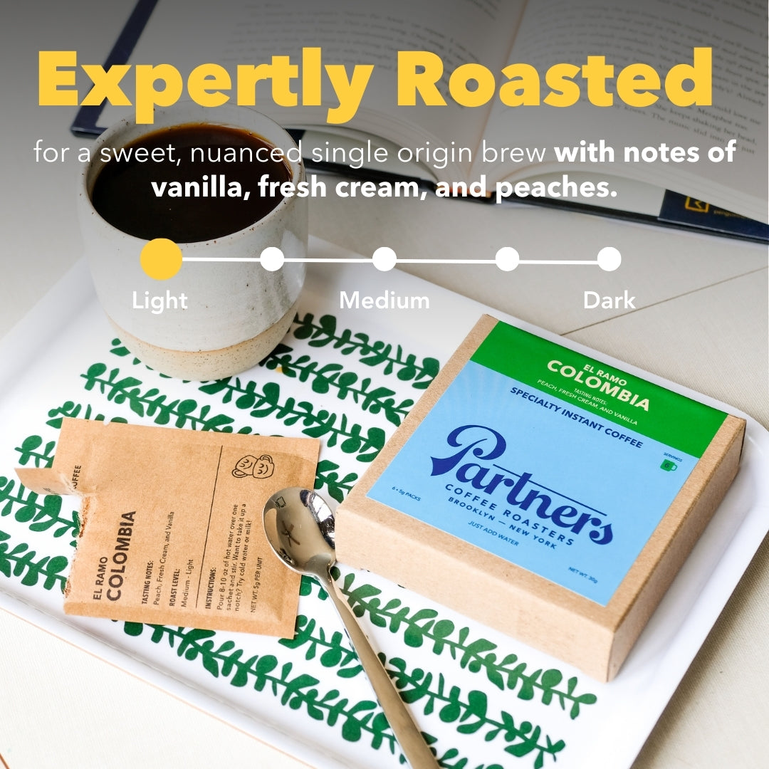 Angled view of El Ramo instant coffee box and pouch with spoon and cup on a tray, ‘Expertly Roasted’ overlay