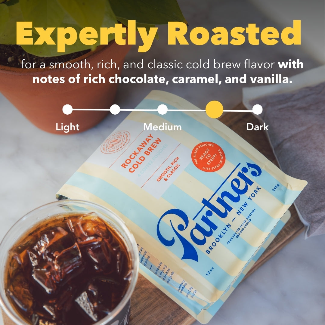 Angled view of Rockaway Cold Brew Pouches showcasing the ‘Expertly Roasted’ roast-level indicator and a glass of iced cold brew