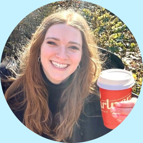 Rachel smiling outdoors while holding a red Partners Coffee takeaway cup