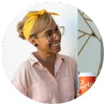 Woman smiling while holding a coffee cup, wearing a yellow headband with a bright background