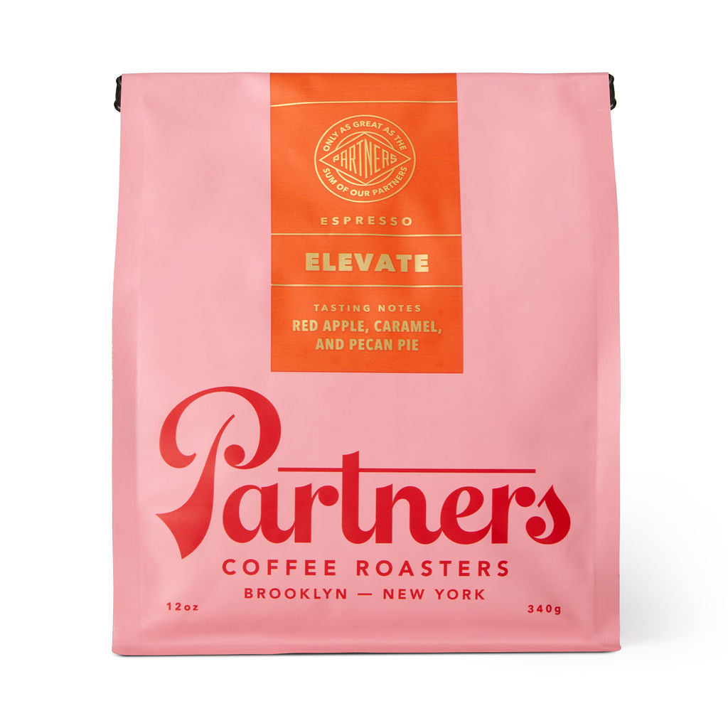 Front view of Elevate coffee bag showing pink packaging with orange label and Partners Coffee logo on white background
