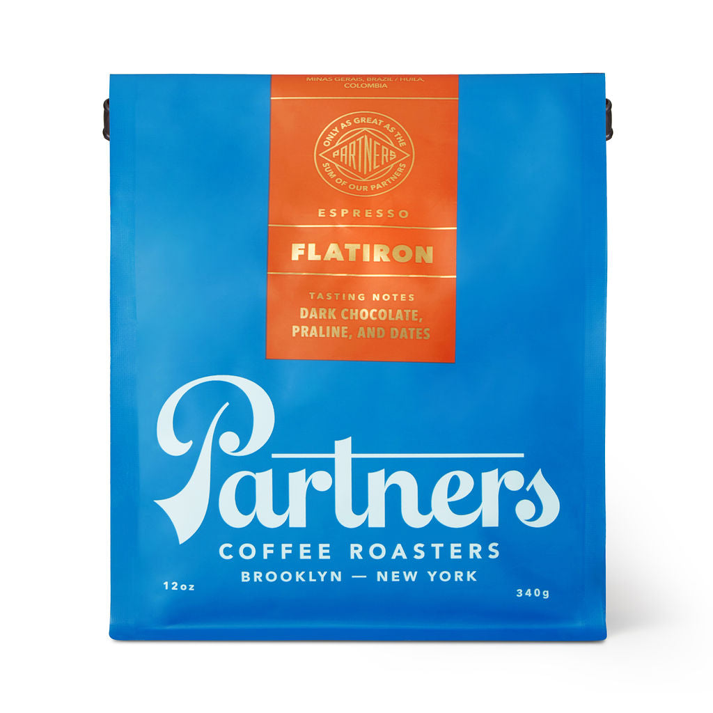 Front view of Flatiron coffee bag showing bright blue packaging, orange label, and large Partners Coffee logo