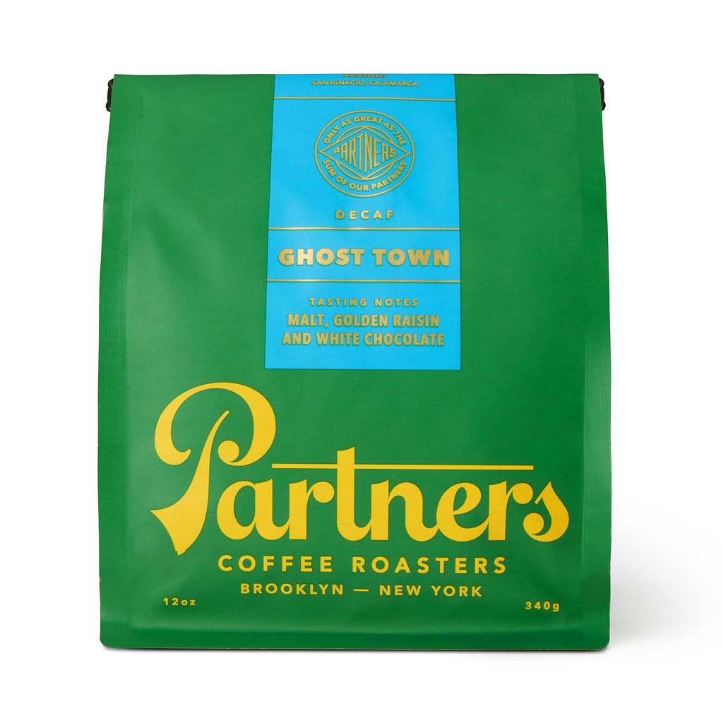 Front view of Ghost Town decaf 12 oz coffee bag showcasing green packaging, blue label with Ghost Town and tasting notes Malt, Golden Raisin and White Chocolate on white background