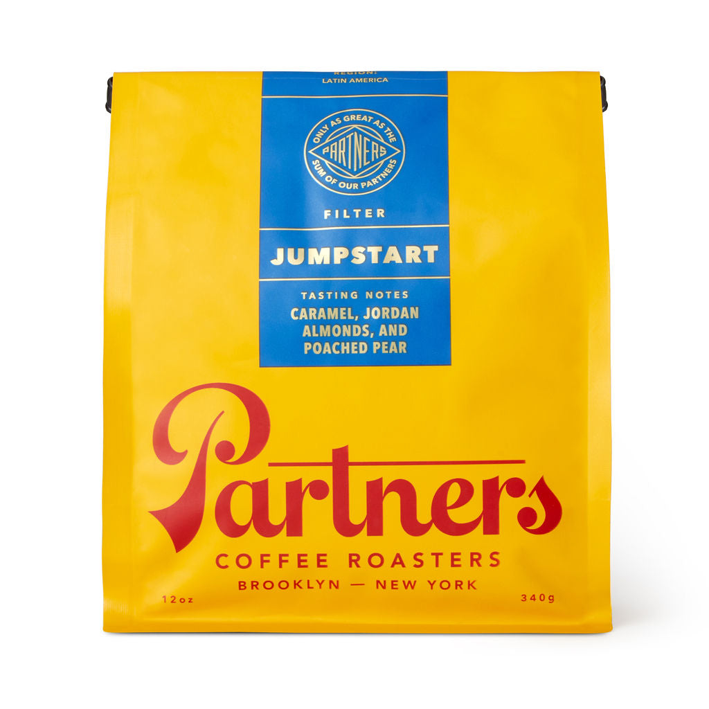 Front view of Jumpstart coffee bag showing yellow packaging with blue label and red Partners logo on white background