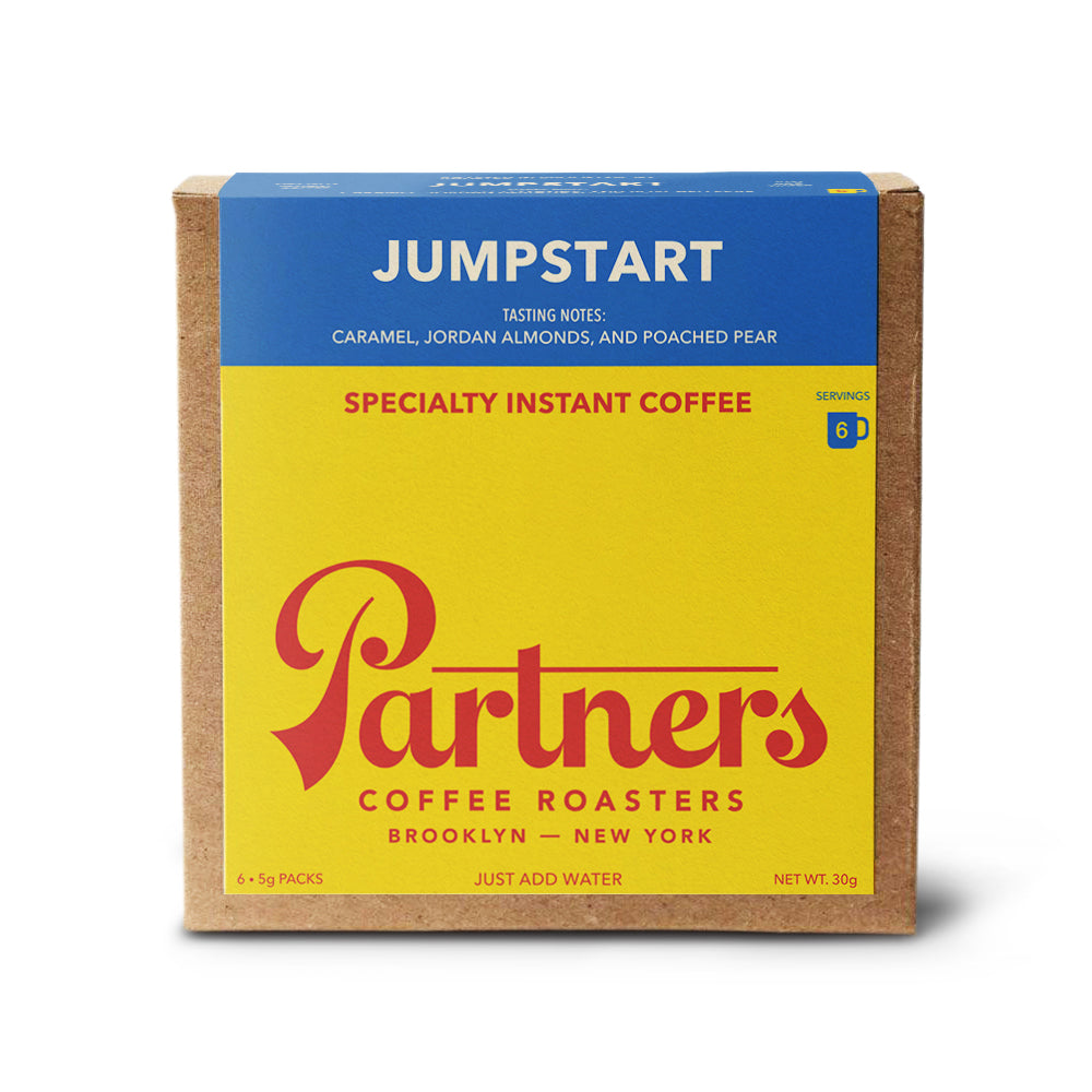 Front view of Jumpstart instant coffee box showing ‘Jumpstart’ headline and Partners logo on yellow and blue packaging, 6 x 5g packs